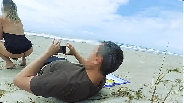 Vacationers look on with disapproval as a milf with her BF films anal content right on the beach